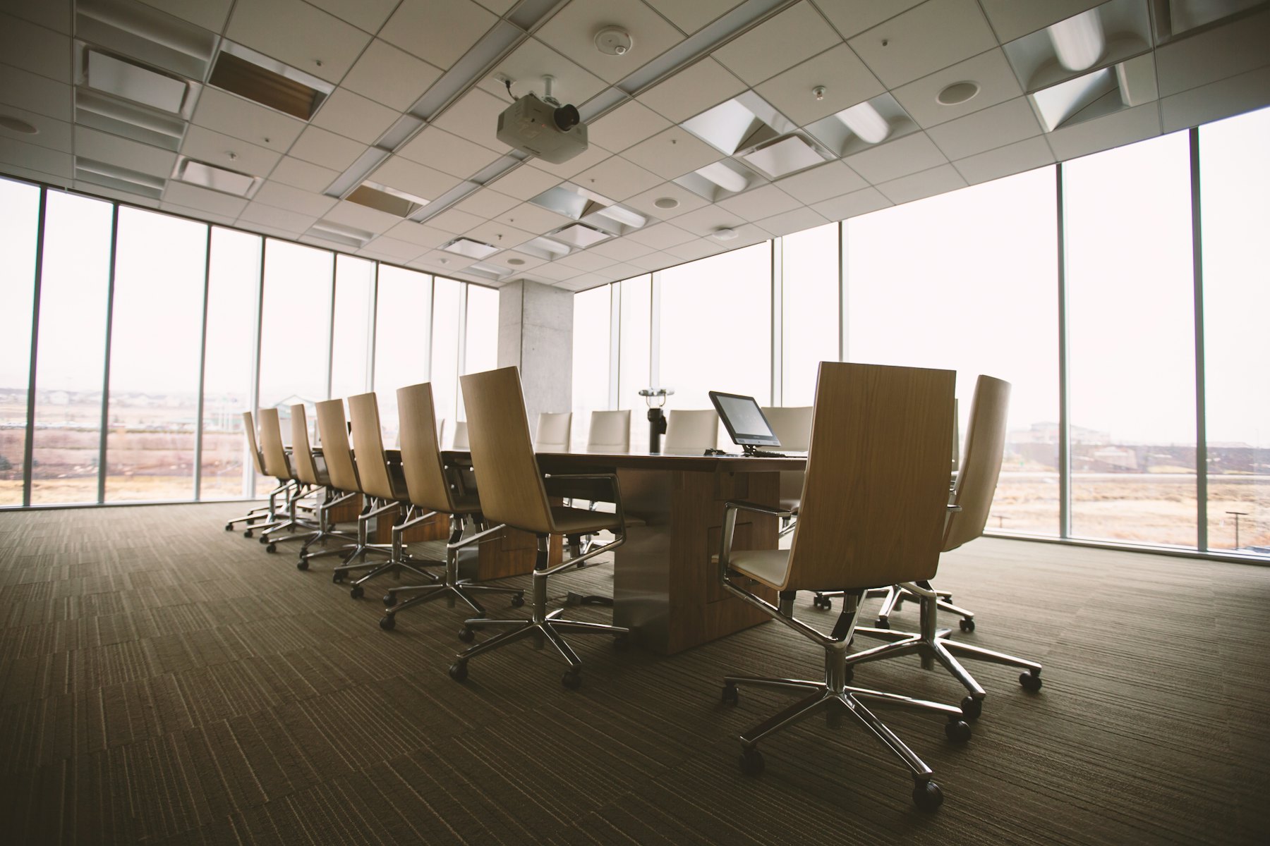 A quiet conference room with a wooden table and floor-to-ceiling windows